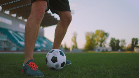 Hochkippen-Mit-Zeitlupe-Eines-Mannes-Aus-Der-Profi-Fußballliga,-Der-An-Einem-Sonnigen-Sommertag-Auf-Dem-Spielfeld-Im-Freien-Mit-Dem-Ball-Am-Bein-Jongliert